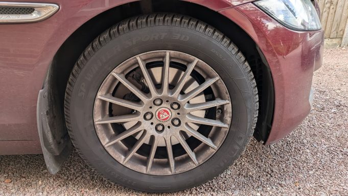 Close-up of a Jaguar XF alloy wheel in Cambridge before detailing, showing heavy brake dust and dirt across the spokes and rim.