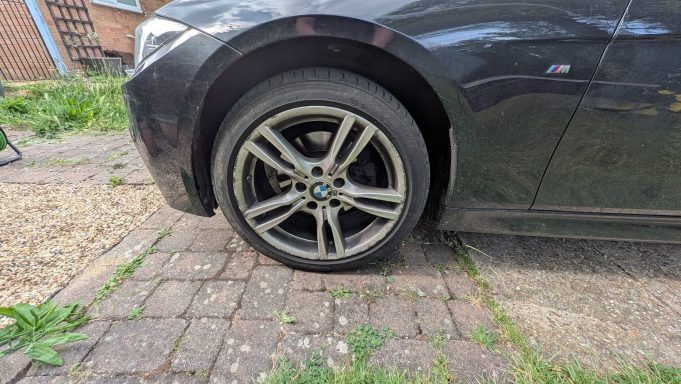 BMW 3 Series alloy wheel before detailing in Stilton, Peterborough Dirty alloy wheel of a black BMW 3 Series in Stilton, Peterborough, showing brake dust and grime before detailing.