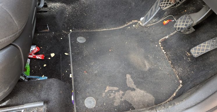Driver’s footwell of a Seat Ateca in Ely, Cambridgeshire before detailing, showing food wrappers, crumbs and staining.