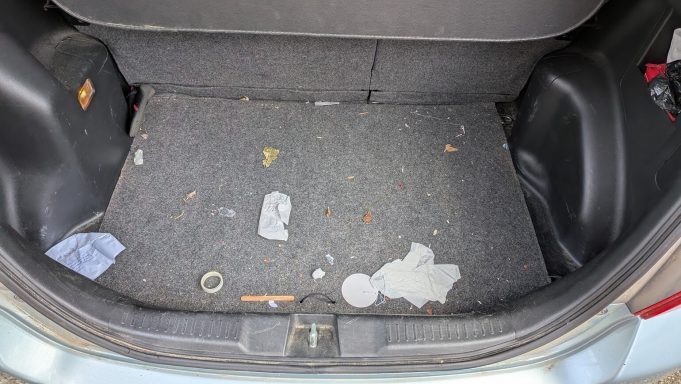 Dirty boot of a Honda Jazz in Market Deeping, Lincolnshire before interior detailing, with litter and debris visible