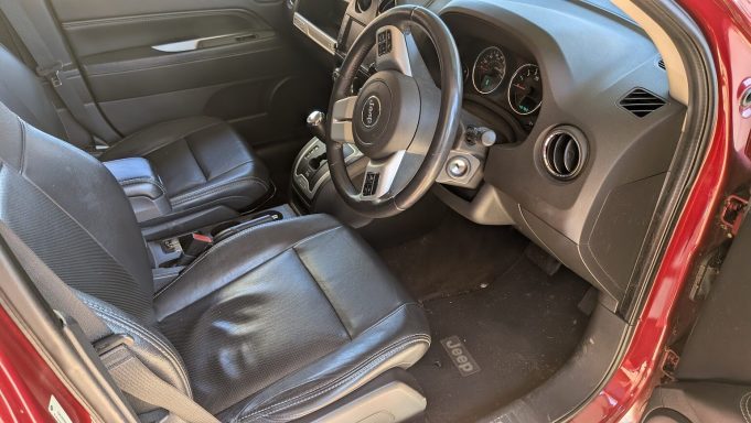 Jeep interior in Mildenhall Suffolk before detailing, black leather seats, dashboard and footwell with dust and debris visible
