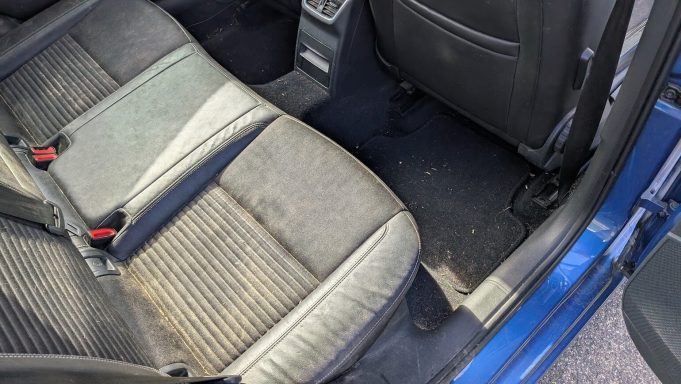 Rear seats of a Skoda in Peterborough, Cambridgeshire before interior detailing, showing dirt, dust and debris across the seats and carpets