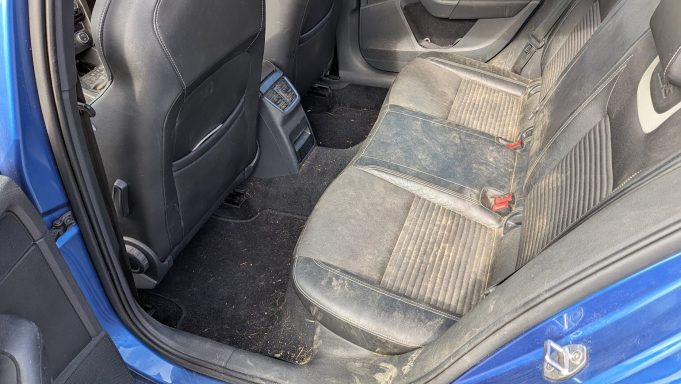 Dirty rear seats of a blue Skoda in Peterborough, Cambridgeshire before interior detailing, showing heavy staining and ground-in debris.
