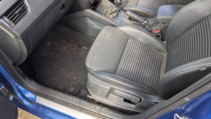 Front passenger seat & footwell of a Skoda in Peterborough, Cambridgeshire before interior detailing, with dirt and debris visible on carpet