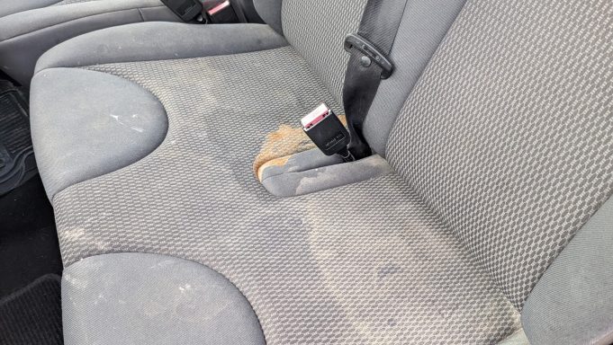 Heavily stained rear seat of a Citroen Berlingo van in Peterborough before extraction cleaning