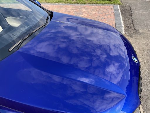 BMW iX1 bonnet in Godmanchester, Cambridgeshire after detailing, high-gloss blue paint reflecting clouds.