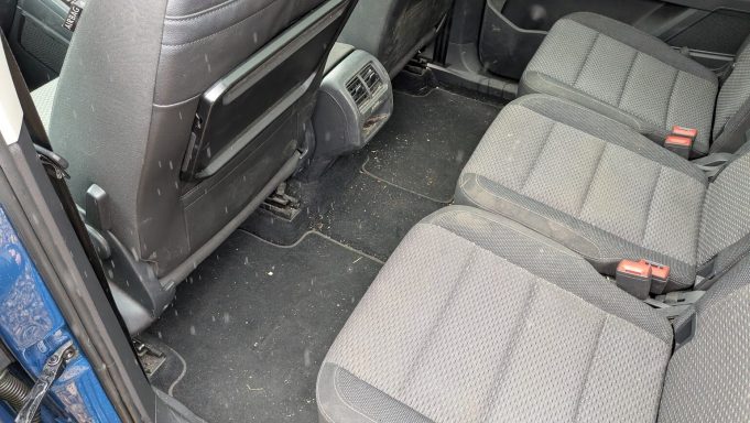 Dirty rear seats and floor of VW Touran in St Ives, Cambridgeshire before interior detailing, with visible debris and dust.