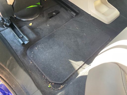 BMW iX1 rear footwell in Godmanchester, Cambridgeshire before interior detailing, carpets with dirt and debris.
